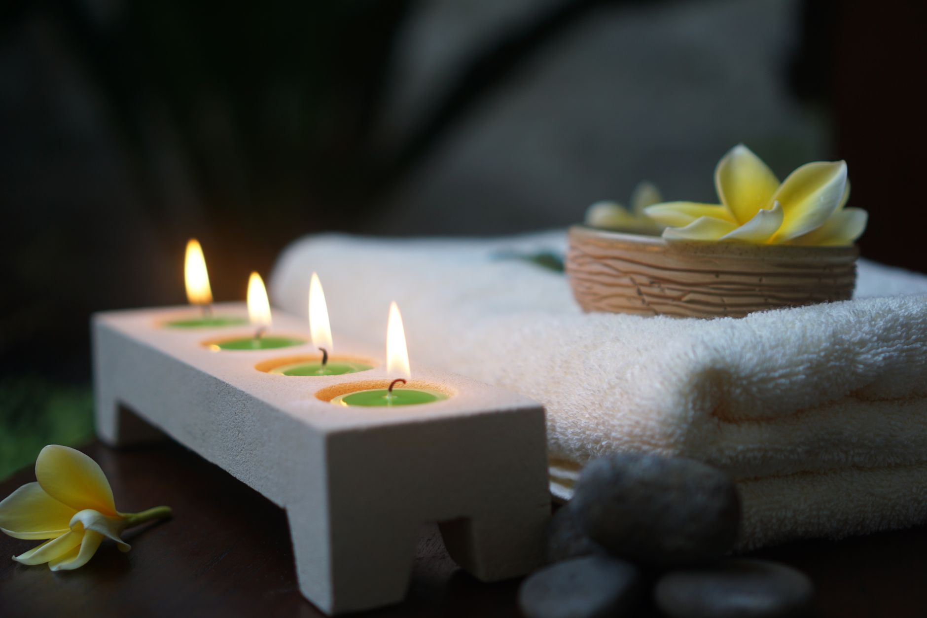Candles, folded towels and warm stones set for a body ritual