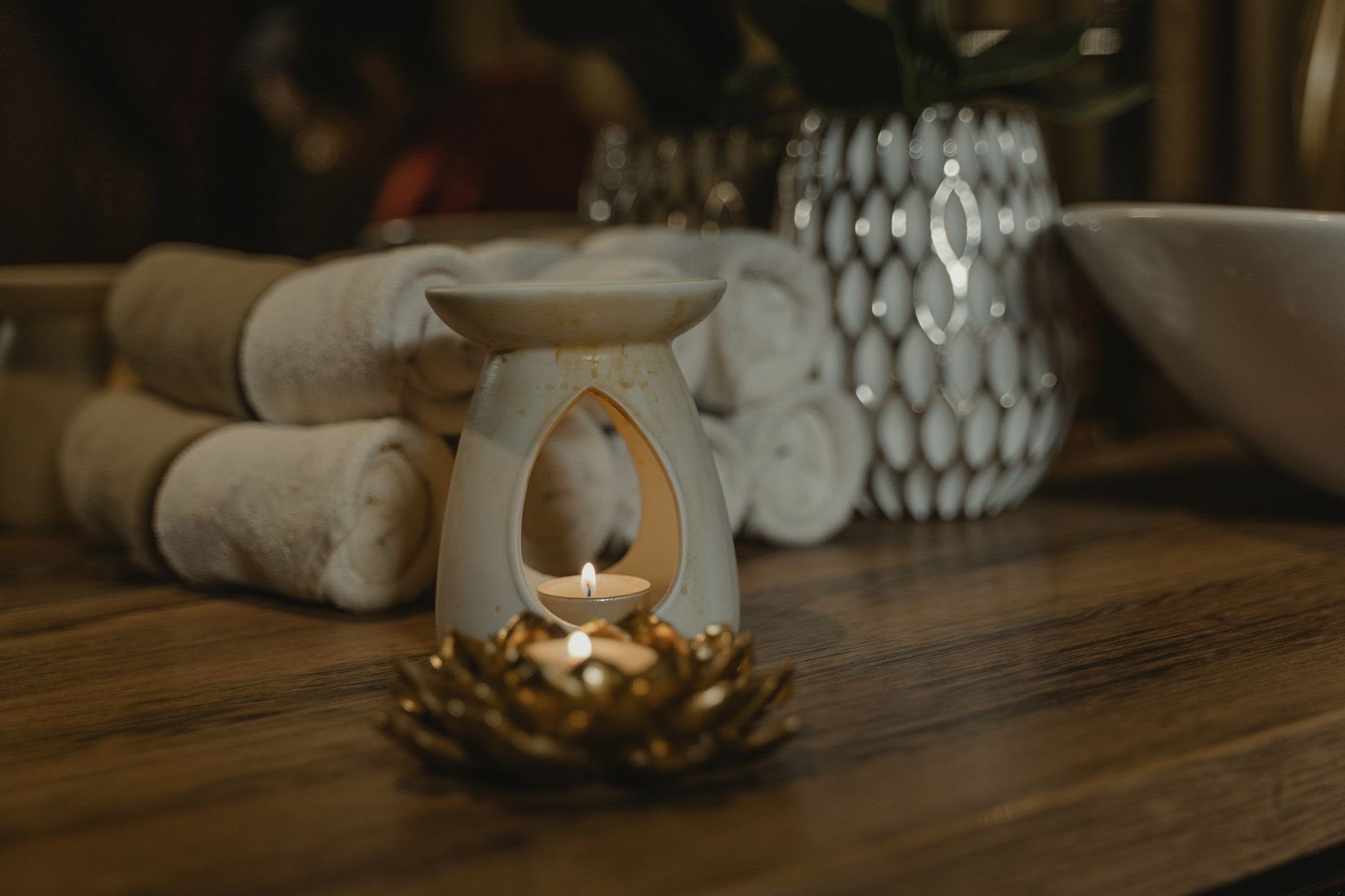 Candlelight over rolled towels in a dark, quiet treatment room
